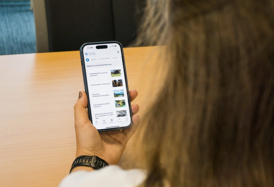 Kvinne som holder mobil med innbyggerapp åpen - Klikk for stort bilde